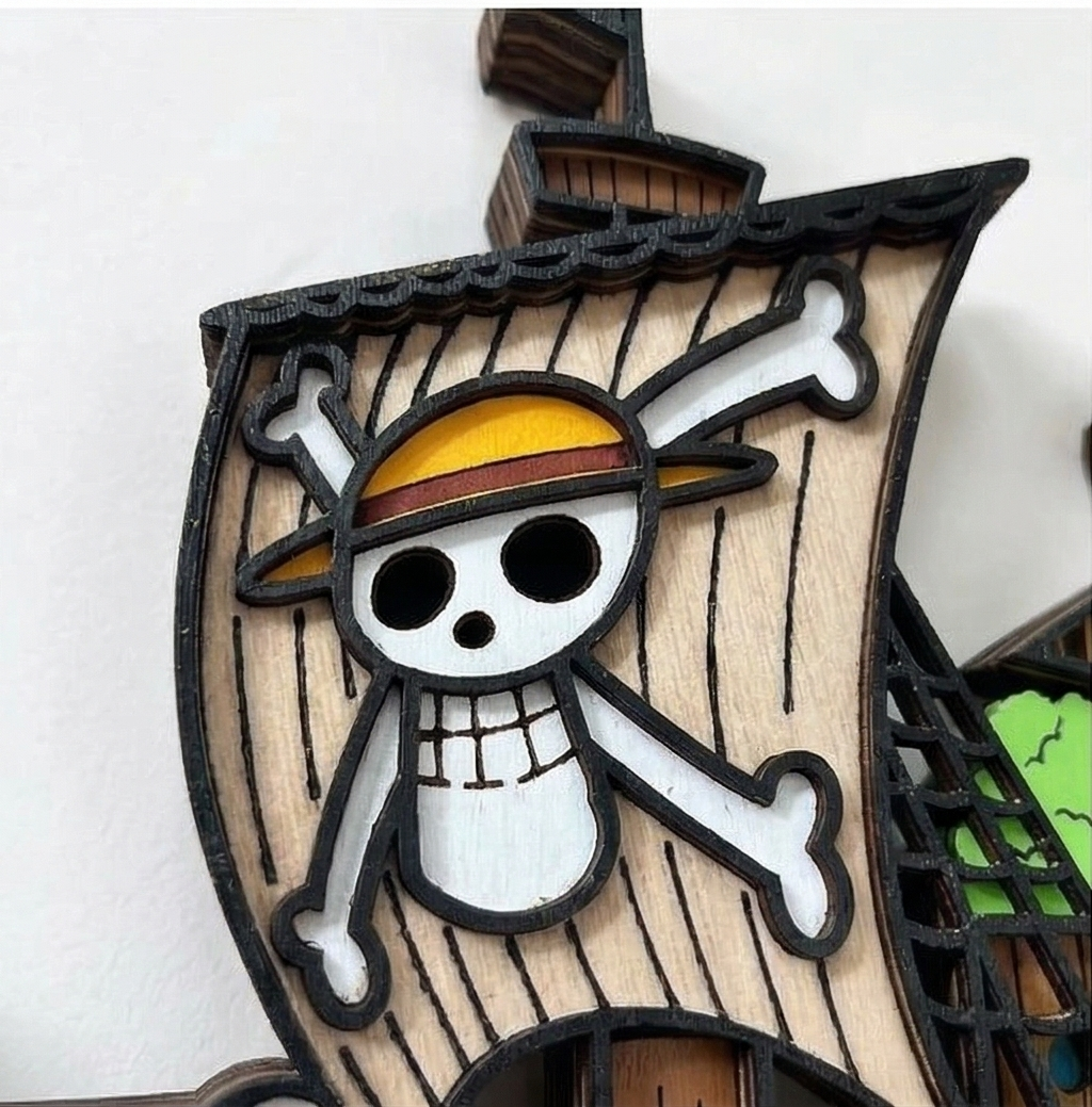 Primer plano detallado del modelo de madera en 3D del barco Going Merry de One Piece, mostrando en detalle el Jolly Roger de la vela principal y su construcción en capas