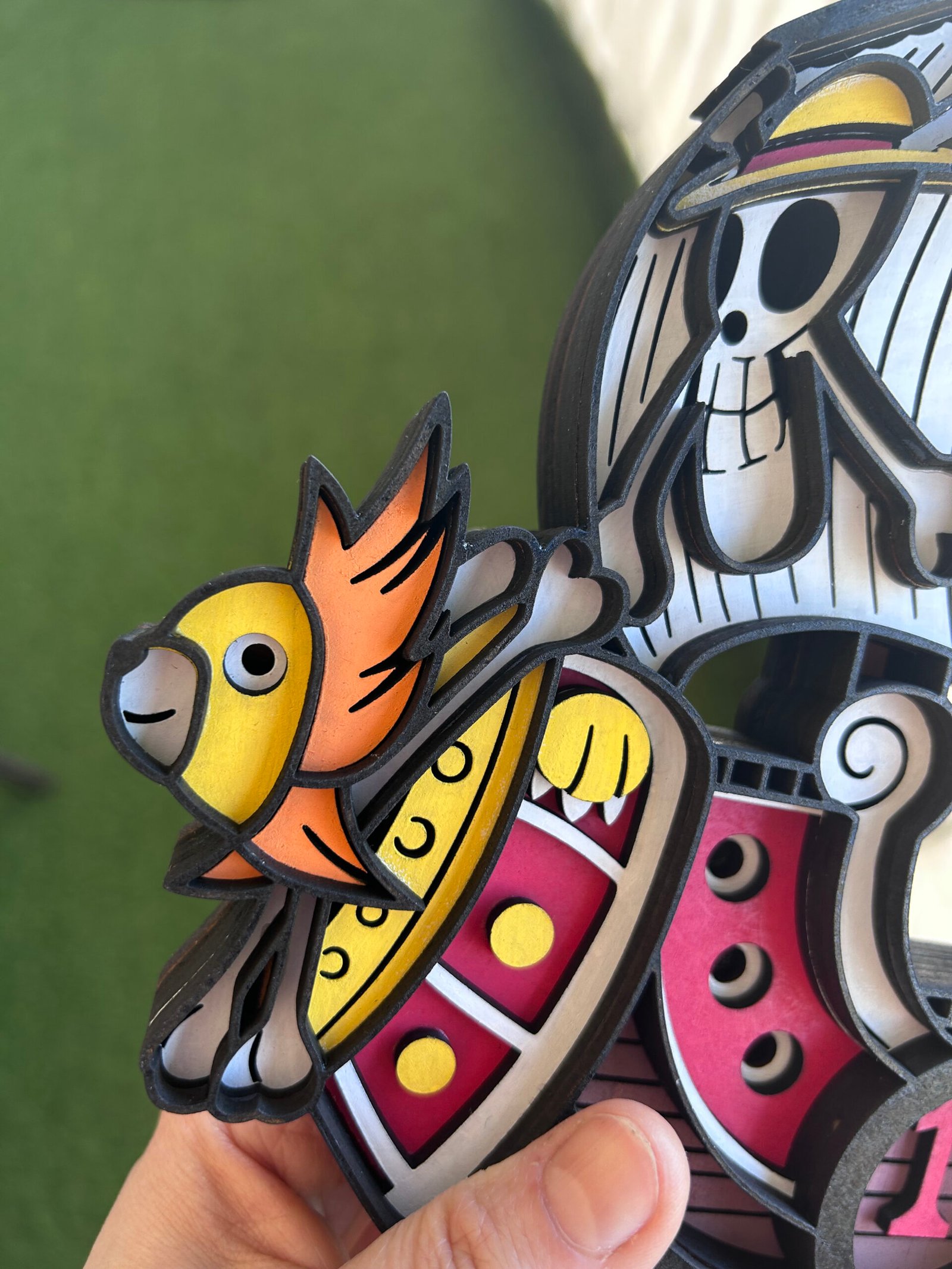 Primer plano detallado del modelo de madera en 3D del barco Thousand Sunny de One Piece, mostrando el mascarón de proa de león y la compleja construcción en capas.
