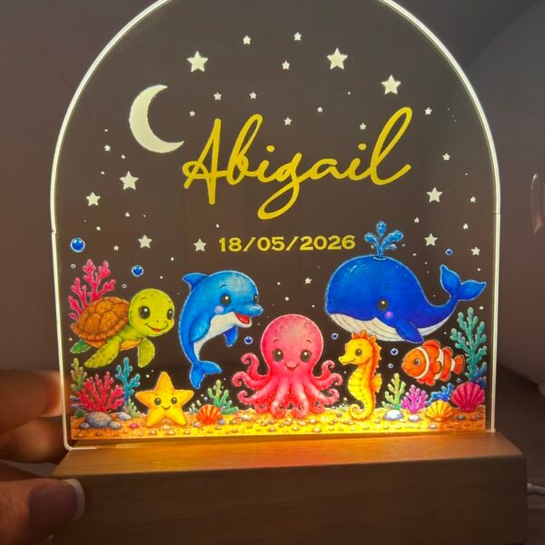 Lámpara de noche LED para bebé personalizada de Yolascraft modelo Mar encendida con el nombre Abigail y fecha de nacimiento, con dibujos del fondo del mar.